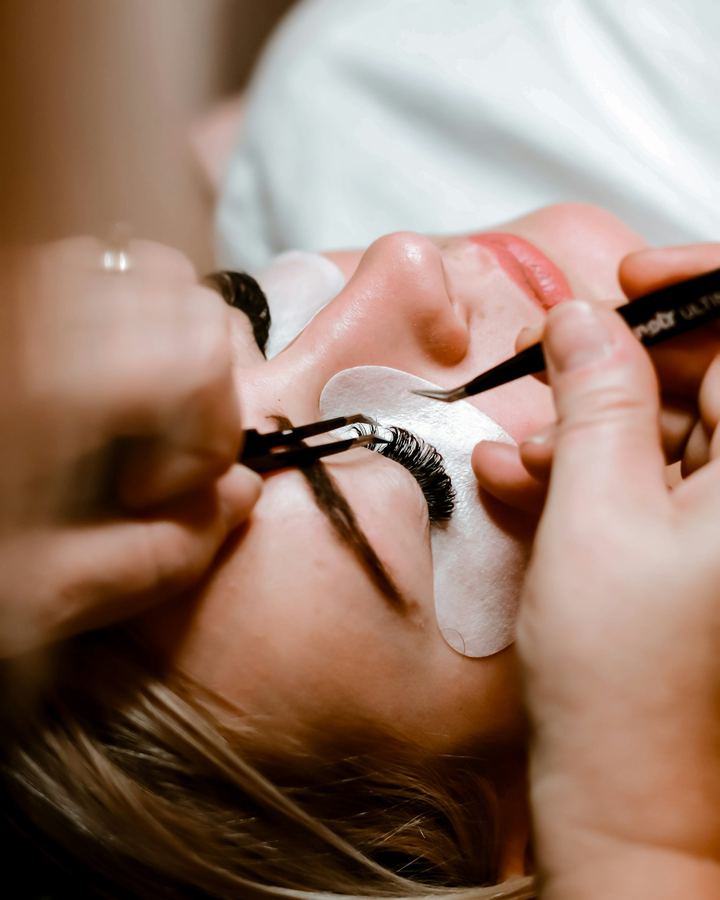 Lash artist placing an extension with tweezers